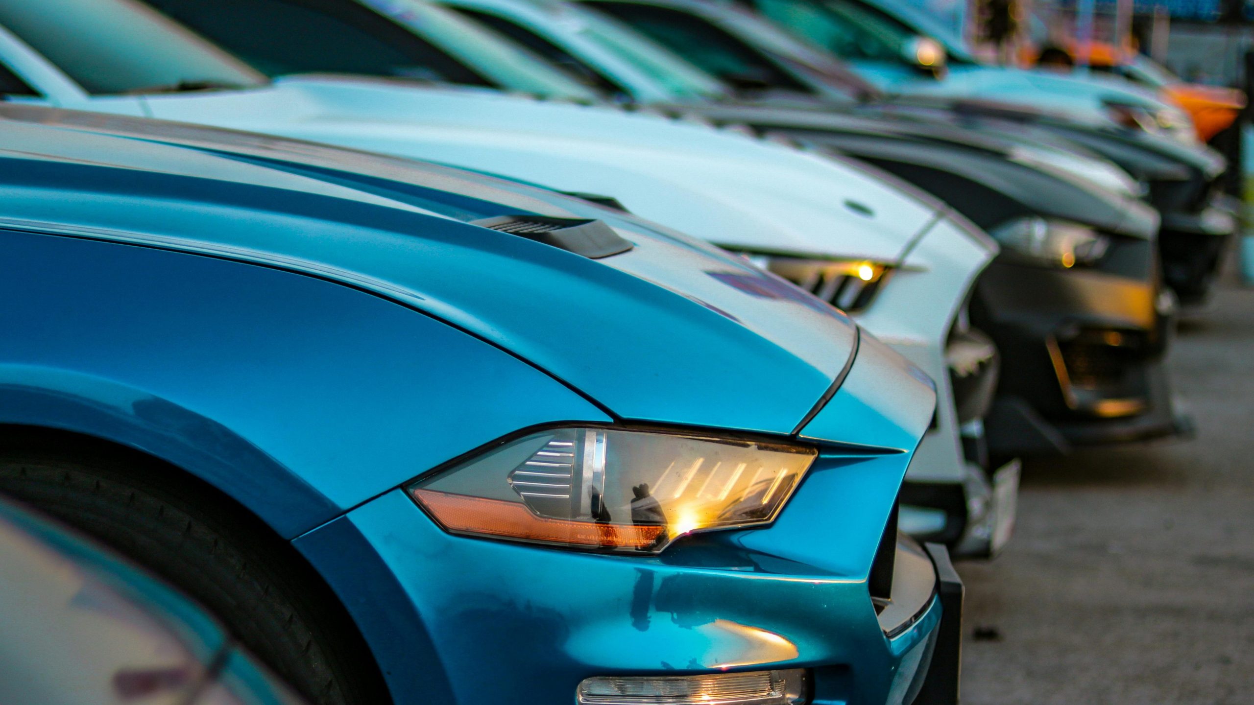 A close-up view of colorful sports cars lined up in an outdoor auto show, showcasing their sleek designs.