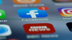 Close-up of smartphone screen displaying various social media app icons including Facebook.