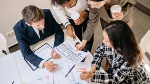 A diverse team in business attire collaborates over graphs and charts for a successful project.