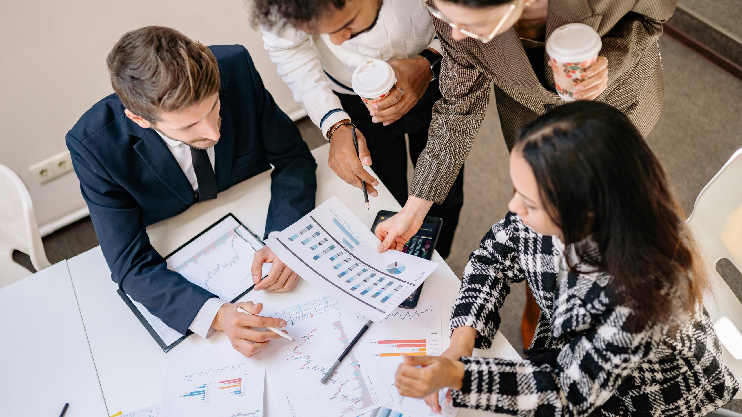 A diverse team in business attire collaborates over graphs and charts for a successful project.