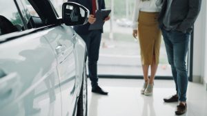 Professional consultation at a car dealership with businesspeople discussing car options.