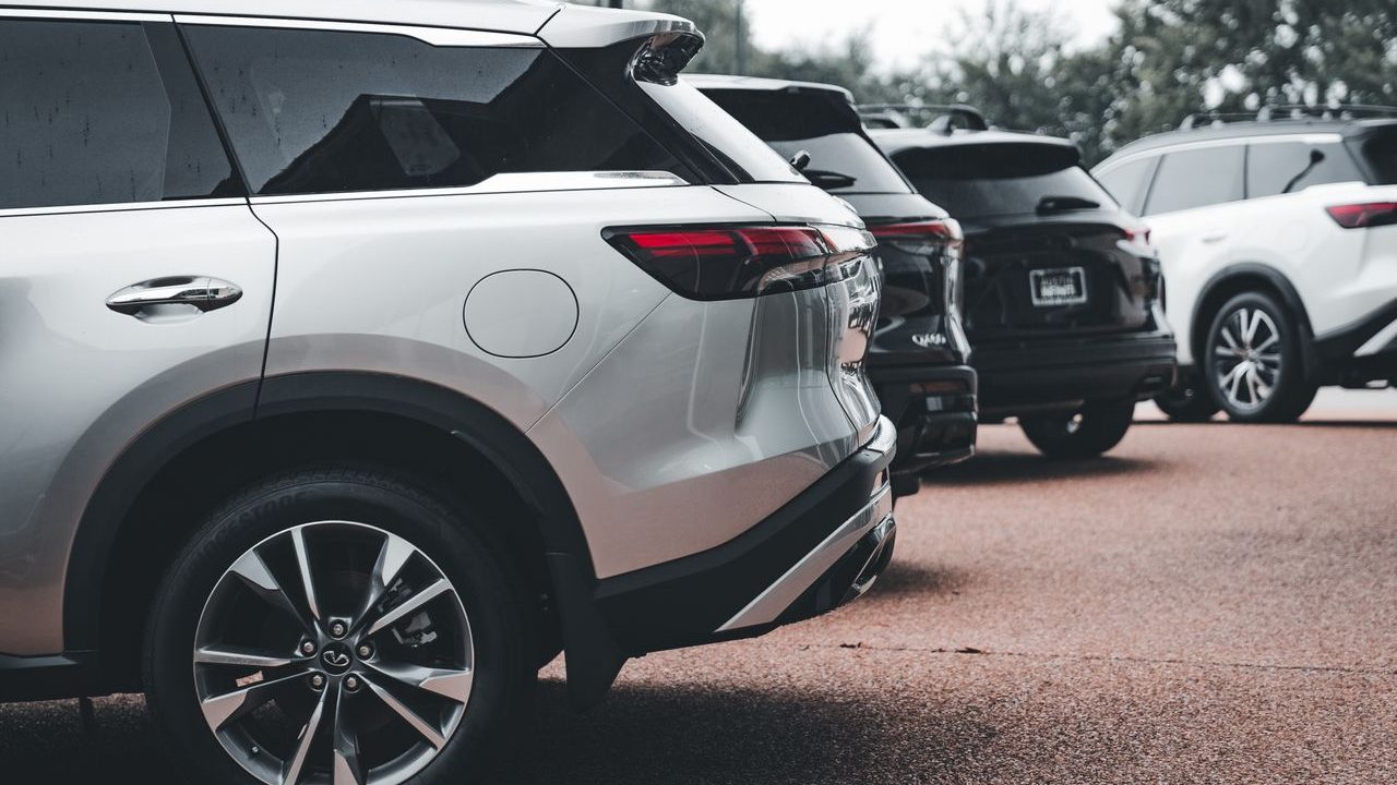 A row of parked SUVs including a silver Infiniti QX60 in an outdoor setting.